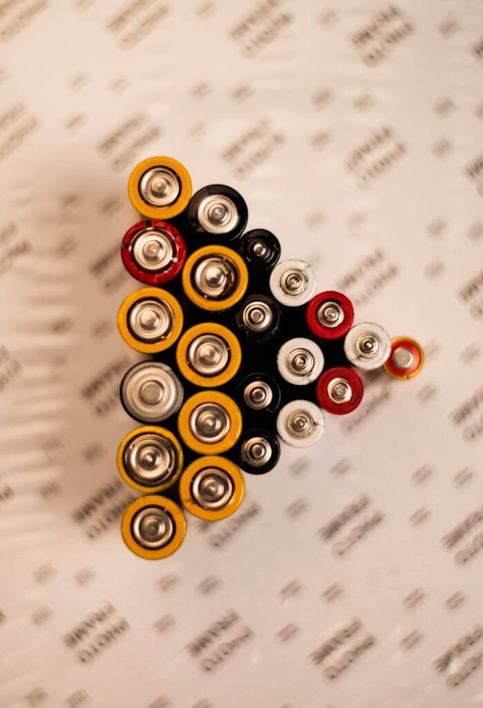 Top view of assorted batteries in an artistic arrangement on a printed surface.
