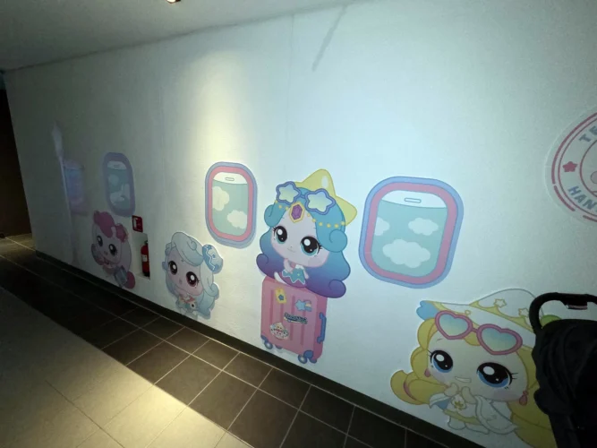 한화리조트 용인 티니핑 객실 복도의 캐릭터와 비행기 창문 모양 벽면 장식