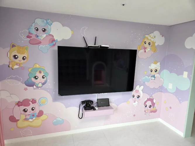 한화리조트 용인 티니핑 연구소룸 큰방의 캐릭터 벽지와 벽걸이 TV, 전화기
